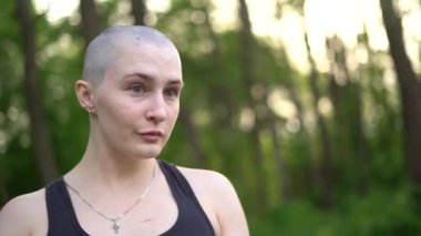 Yeşil arka planda poz veren kel bir kız.