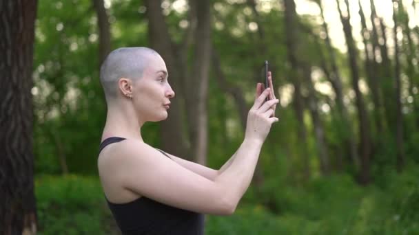 Skallig Flicka Med Mobiltelefon Poserar Naturen — Stockvideo