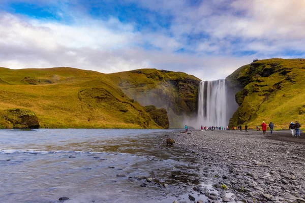 Skogafoss waterfall seen from afar with unrecognisable visitors, — 스톡 사진
