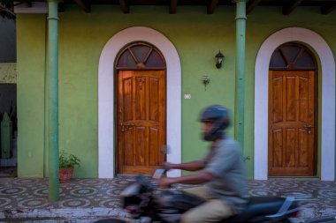 Motosikletçi ve açık yeşil ev Fontainhas, Panaji, Goa 'da.
