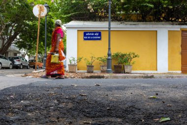 Pondicherry, Hindistan - 19 Mart 2018: Parlak renkler giyen tanınmayan kadın Fransızca bir sokak tabelasının yanından geçiyor