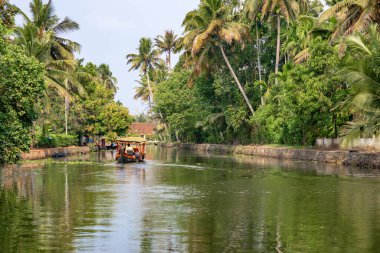 Alleppey, Kerala, Hindistan - 30 Mart 2018: Palmiye ağaçlı durgun kanal. Sabahleyin kameraya uzaktan yaklaşan küçük bir tekneyle çekildi..