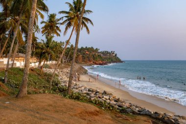 Varkala, Kerala, Hindistan - 2 Nisan 2018: Gün batımında küçük Varkala plajı. Güneşli bir ilkbaharda öğleden sonra sahilde birkaç kişiyle çekilmiş.