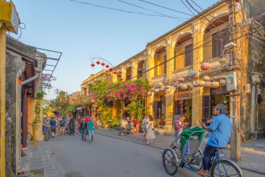 Hoi An, Vietnam - 11 Nisan 2018: Hoi An ana caddesinde ön planda bir triportörle kalabalık