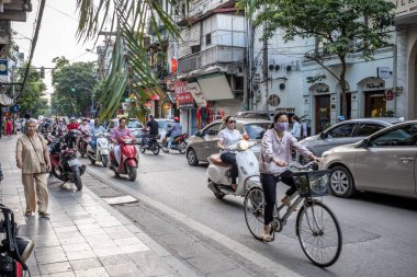 Hanoi, Vietnam - 30 Nisan 2018: Yerlilerin kalabalık bir caddede motosikletlerini veya motosikletlerini sürdükleri sokak sahnesi.