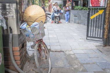 Hanoi, Vietnam - 28 Nisan 2018: Hasır şapka, bisiklet ve arka planda bazı insanlarla sokak sahnesi