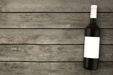 Şarap şişesi ahşap masanın üstünde.