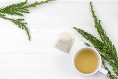Morning tea cup serves on white wood panel decorate with pine tree branch