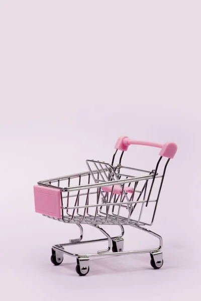 Pembe arka planda Pastel pembe minyatür alışveriş arabası