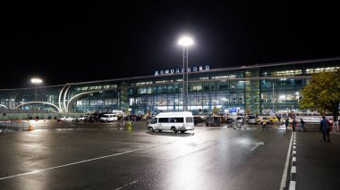 Moskova / Rusya - 18 Ekim 2019: Gece vakti uluslararası Domodedovo havaalanı binasının dışı. İnsanlar terminalin yanında yürüyorlar. Parlak ışıklar parlıyor.