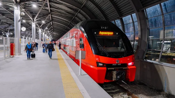 Moskova / Rusya - 18 Ekim 2019: Aeroexpress çift katlı tren akşam saatlerinde Domodedovo havaalanı istasyonunda. İnsanlar platformda yürüyor.