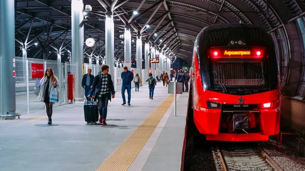 Moskova / Rusya - 18 Ekim 2019: Aeroexpress çift katlı tren akşam saatlerinde Domodedovo havaalanı istasyonunda. İnsanlar platformda yürüyor.