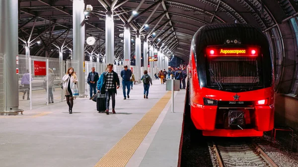 Moskova / Rusya - 18 Ekim 2019: Aeroexpress çift katlı tren akşam saatlerinde Domodedovo havaalanı istasyonunda. İnsanlar platformda yürüyor.