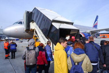 Moskova / Rusya - 16 Mart 2020: Sheremetyevo Havaalanı 'ndaki Airbus A320 Aeroflot' a yolcu alımı. Bir yolcu kalabalığı bir uçak rampasının önünde duruyor..