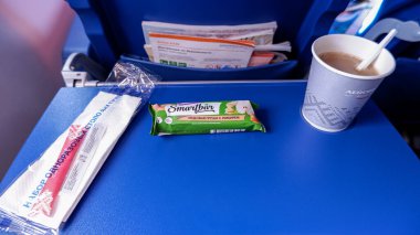 Moskova / Rusya - 16 Mart 2020: Uçuş sırasında Aeroflot uçağında yemek. Meyve barı ve bir fincan kahve mavi koltuk masasında..