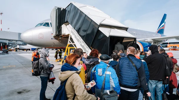 Moskova / Rusya - 16 Mart 2020: Sheremetyevo Havaalanı 'ndaki Airbus A320 Aeroflot' a yolcu alımı. Bir yolcu kalabalığı bir uçak rampasının önünde duruyor..
