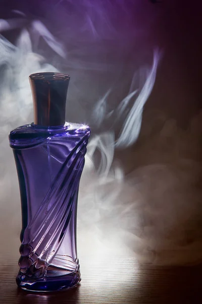 Schöne lila Flasche weibliches Parfüm im Rauch — Stockfoto