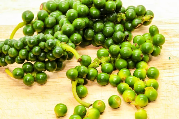 Sraženiny čerstvých zelených peppercornů na hnědém dřevěném — Stock fotografie