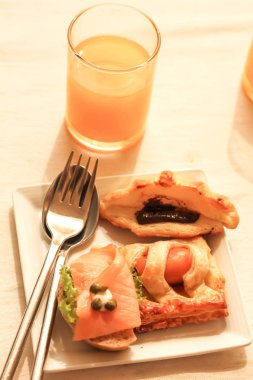 Ekmek ile çikolata, sosis, somon füme ve portakal suyu