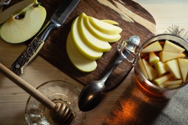 Bardakta elma, kaşık ve bıçak ve bal ve bal kaşığıyla dilimlenmiş meyve ile dolu bir hayat. Evde sıcak bir içecekle iyi eğlenceler. Üst görünüm