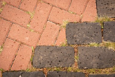 Kaldırım fayansının üst görüntüsü çapraz sırayla. Dikdörtgen seramik terracotta ve gri seramik seramik seramik kiremitler ve bölümler halinde yeşil çimen demetleri.