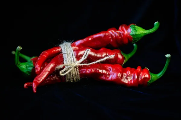 Mavi arka planda keskin kırmızı biberler kaba bir iple bağlanır. Sağlıklı yemek için sebze menüsü.