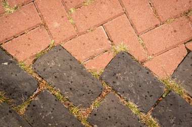 Kaldırımlar açık kırmızı, turuncu ve koyu kahverengidir ve eklemlerinde genç otlar vardır. Kentsel yaşam ve doğa için arka plan.