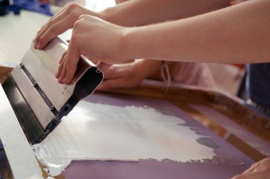 Spatula ya da bıçak, çizim yapmak ya da elle baskı yapmak için esnetilmiş bir tuvale kalın boya sürmek için. Eller kumaş çizmek için yaratıcı işler yapıyor..