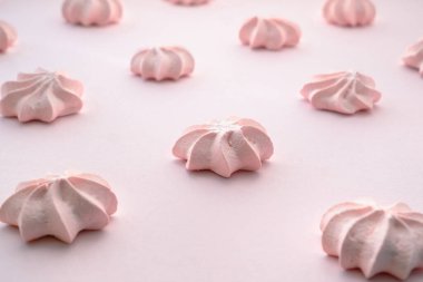 Aerial dessert of whipped egg whites with small hills on pink top. Gentle lilac rows on a flat surface of a similar color.