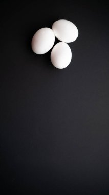 Koyu siyah pürüzsüz yüzeyde bir grup tavuk yumurtası. Haşlanmış protein ürünlerinin sağlıklı kahvaltısı.