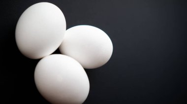 Siyah arka planda haşlanmış ya da çiğ tavuk yumurtası. Katranlı rulo ile sağlıklı dengeli yemek.