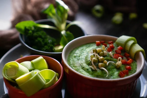 Sağlıklı dengeli bir diyetin parçası olarak patates püresine dayalı ıspanaklı, pırasalı ve brokolili bir kase yeşil vegan kremalı çorba..