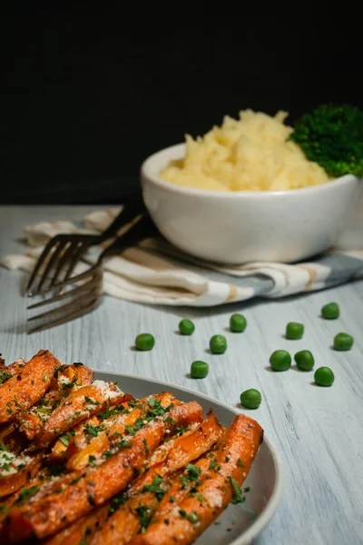 Vegan dinner with organic vegetables for healthy eating. Baked carrots with greens and mashed potatoes and broccoli