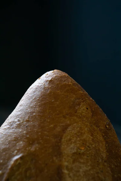 Siyah arka planda taze bir somun ekmeğin kenarı. Maya ürünü..