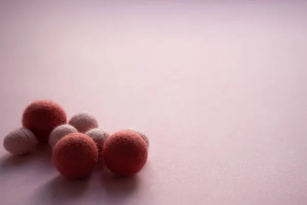 一组深色的大小轻毛球堆积在光滑的粉红色表面上 用针头擦干毛毡 — 图库照片