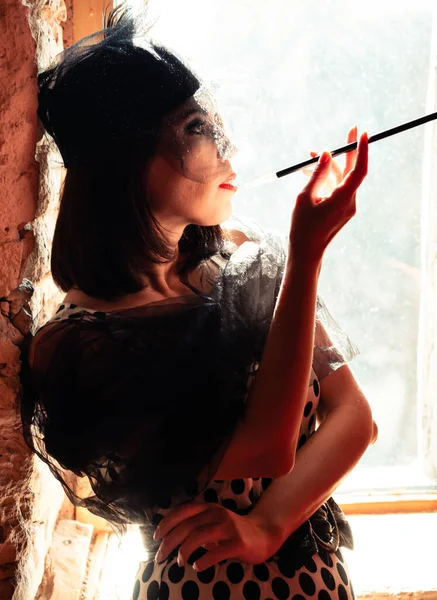 Gatsby partisinde retro kostümlü bir kadının portresi. Uzun güzel parmakları olan bir ağızlık..