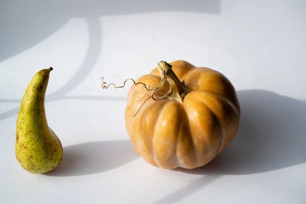 Still life of ingredients for vegan food on a white surface. Vegetable pumpkin and fruit pear conference on healthy food menu.