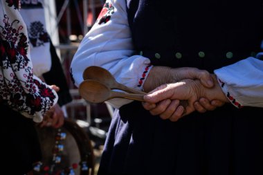 Geleneksel Ukrayna nakışlı ulusal kostüm giymiş yaşlı bir kadının ellerinde iki tahta kaşık..