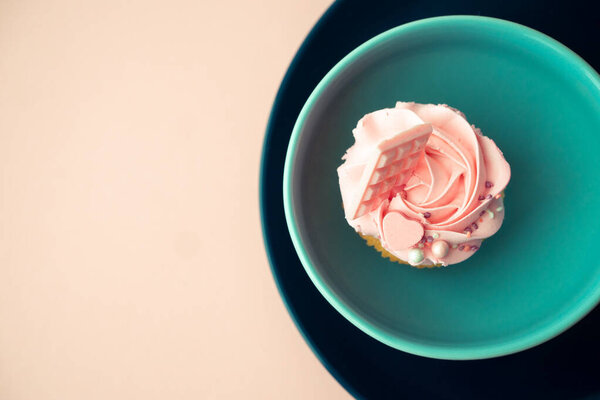 Круглая форма голубых тарелок и розового теста со сливочным кремом на розовой поверхности. Кекс в подарок на праздник или девичник.