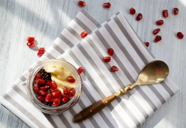 Taze nar meyveleri, muz ve ayçiçeği tohumları çikolatalı granola ile yoğurtlu chia pudingi. Sabahları kullanışlı ürünlerle dengeli beslenme.