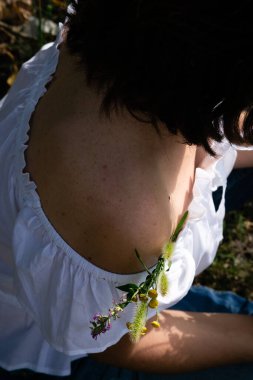 Kotlu siyah saçlı, yaz çimlerinde oturan çekici, çıplak bir kadın.