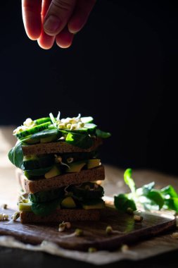 Taze sebze ve avokado ile dengeli ekmek rulosu. Vejetaryen sandviçin içinde salatalık ve fasulye filizi..