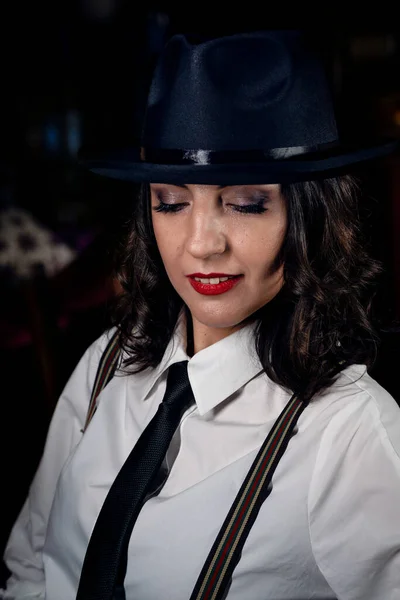 Mafia game in restaurant. Beautiful woman in gangster image in hat and white shirt