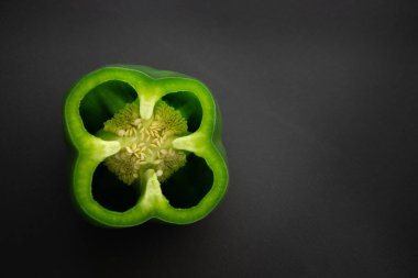 Yeşil dolma biber koyu bir yüzeyde ikiye bölünmüş. Bahar salataları için sulu olgun sebze vitamini.