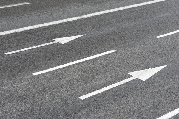 Flechas blancas señales en un camino urbano de asfalto — Foto de Stock