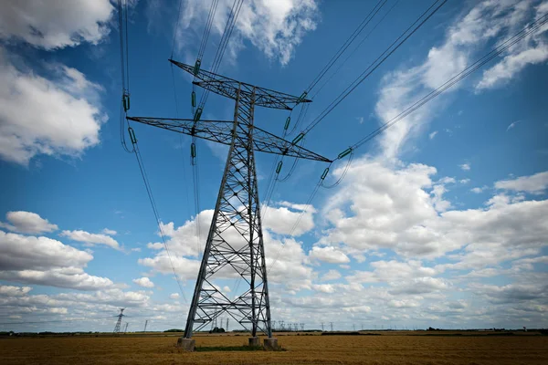 High voltage pylons on blue cloudy sky — Stock Photo, Image