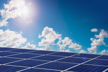 Fotovoltaik panel ve güneş parlıyor mavi bulutlu gökyüzü arka plan