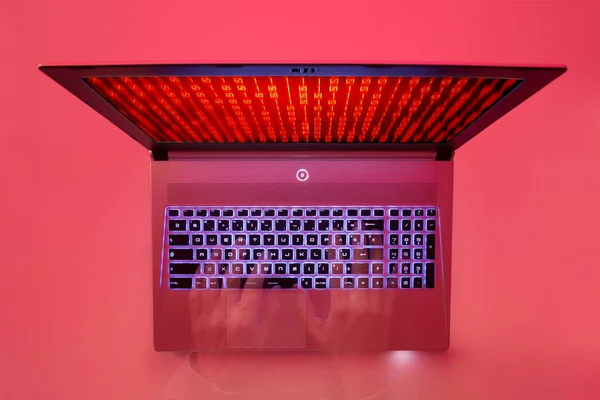 双手在笔记本电脑键盘上键入红色零和一个数字在屏幕上滚动 顶部视图 红灯背景 — 图库照片