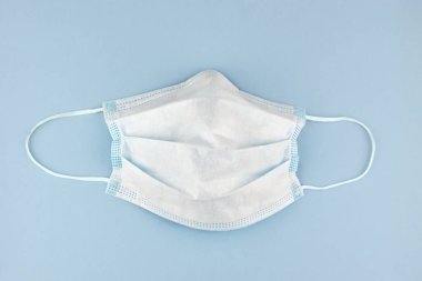 Soluk mavi arka planda Coronavirus gibi virüslere karşı cerrahi koruma maskesi