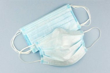 Soluk mavi arka planda Coronavirus gibi virüslere karşı cerrahi koruma maskesi